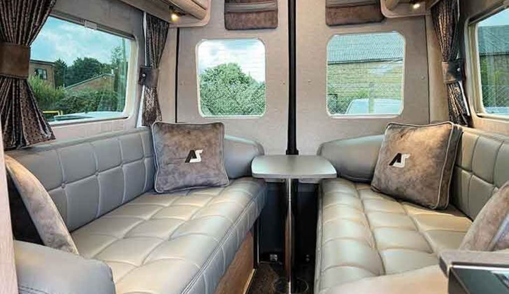 A cozy campervan interior with Black Leatherette seats, climate control, and custom cabinetry