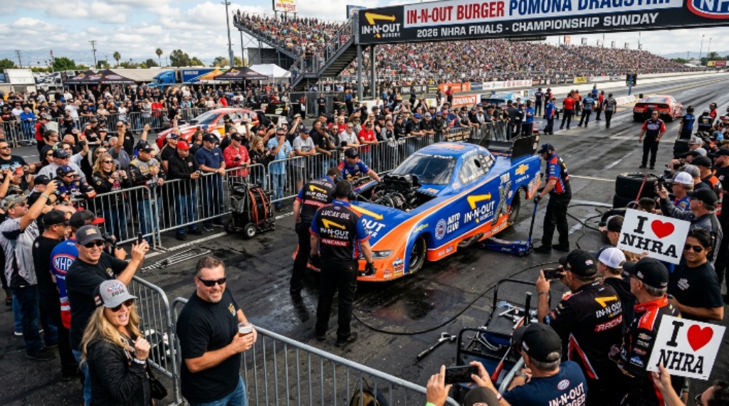 Fans lining the pit area at the In-N-Out Burger Pomona Dragstrip during the 2026 NHRA Finals, watching crew members prepare a Funny Car between elimination rounds on championship Sunday